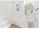 Bright powder room featuring a pedestal sink, oval mirror, and natural light from a window at 348 Autumn Pheasant Loop, Calabash, NC 28467
