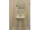 Pedestal sink with an oval mirror in a neutral-colored powder room featuring minimal decor at 8743 Baton Rouge Ave Nw, Calabash, NC 28467