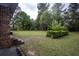 Lush backyard featuring a brick home and a lawn with mature trees adding natural charm at 1001 Creel St., Conway, SC 29527