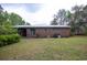 A brick home's backyard with a metal roof, patio, and grassy lawn surrounded by mature trees at 1001 Creel St., Conway, SC 29527