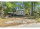 Gray mobile home nestled on a treed lot featuring light-filled windows and a charming home for simple living at 103 Off Shore Dr., Murrells Inlet, SC 29576