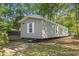 Gray manufactured home with white trim nestled among mature trees on a sunny day at 103 Off Shore Dr., Murrells Inlet, SC 29576