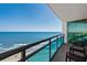 Enjoy ocean views from this balcony with seating, glass railings, and access to the home's interior through sliding glass doors at 107 S Ocean Blvd. # 1201, Myrtle Beach, SC 29577
