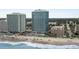 Bright aerial view of beach front property, ocean, and white sandy beach complete with beach goers and crashing waves at 107 S Ocean Blvd. # 1201, Myrtle Beach, SC 29577