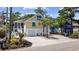 Charming yellow home with blue shutters, a two-car garage, and lush landscaping in a desirable community at 1114 S Dogwood Dr., Surfside Beach, SC 29575