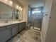 Bathroom featuring dual sinks, tiled shower, and gray cabinets at 1233 Lady Bird Way, North Myrtle Beach, SC 29582