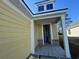 Home entryway featuring brick accents, white columns, light yellow siding, and partially open front door at 1233 Lady Bird Way, North Myrtle Beach, SC 29582