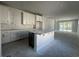 Unfinished kitchen with a large island, white cabinets, and stainless steel appliances wrapped in plastic at 1233 Lady Bird Way, North Myrtle Beach, SC 29582