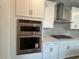 Close-up of stainless steel oven and stove with white cabinets and modern backsplash at 1233 Lady Bird Way, North Myrtle Beach, SC 29582