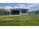 Rear view of the home featuring a screened in porch surrounded by an expansive green lawn at 1233 Lady Bird Way, North Myrtle Beach, SC 29582