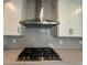 Close-up of stainless steel stovetop, hood, and tiled backsplash with white cabinets at 1233 Lady Bird Way, North Myrtle Beach, SC 29582