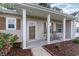 Inviting front porch with rocking chairs, decorative columns, and landscaped flowerbeds enhance curb appeal at 180 Oak Crest Circle, Longs, SC 29568