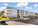 Four-story condo building with white exterior, multiple balconies, parking lot, and palm trees at 191 Maison Dr. # B-319, Myrtle Beach, SC 29572