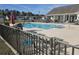 Large community swimming pool featuring lounge chairs, tables, umbrellas, and fencing under a partially cloudy sky at 213 Cupola Dr., Longs, SC 29568