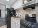 Compact kitchen with stainless steel sink, white cabinets, and black appliances at 2401 S Ocean Blvd. S # 1256, Myrtle Beach, SC 29577