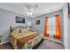Bedroom with ceiling fan, bed with colorful floral comforter, and window with bright orange curtains at 254 Tall Palms Way, Little River, SC 29566