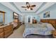 Spacious main bedroom with blue walls, tray ceilings, a ceiling fan, and matching dresser set at 254 Tall Palms Way, Little River, SC 29566