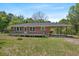 Charming brick home featuring a wooden deck, convenient carport, and lush green surroundings at 2865 N Nichols Hwy., Nichols, SC 29581