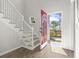 Bright foyer with wood floors, white staircase, and a red front door opening to a landscaped yard at 405 Emerson Dr., Myrtle Beach, SC 29579