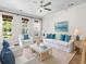 Cozy living room with white sofas, blue pillows, wicker furniture, and multiple sunny windows at 405 Emerson Dr., Myrtle Beach, SC 29579