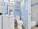 Light blue bathroom with white cabinets, toilet, vanity and neutral tile flooring at 5511 N Ocean Blvd. # 203, Myrtle Beach, SC 29577