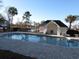 Community pool with a paved deck beside a bathhouse, landscaping, and a pond on a sunny day at 573 Blue River Ct. # 8-H, Myrtle Beach, SC 29579