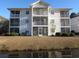 Condo building with multiple screened porches and a tranquil waterway view at 573 Blue River Ct. # 8-H, Myrtle Beach, SC 29579