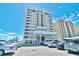 Exterior of condo complex featuring lush landscaping, covered parking, and stunning architecture against a bright blue sky at 6200 N Ocean Blvd. # 203, North Myrtle Beach, SC 29582