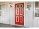 A bright red front door is adorned with decorative nautical art and flanked by windows and a light fixture at 634 Melody Ln., Surfside Beach, SC 29575