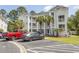 A multi-story building with exterior balconies, surrounded by palm trees and meticulous landscaping at 646 Tupelo Ln. # 4E, Longs, SC 29568