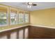 Bright, unfurnished bedroom with a ceiling fan, hardwood floors and large windows offering a view of lush greenery at 808 East Coast Ln., North Myrtle Beach, SC 29582