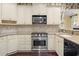 Bright kitchen with granite countertops, stainless steel appliances, and custom cabinets with a decorative wallpaper accent at 808 East Coast Ln., North Myrtle Beach, SC 29582