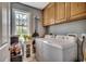 Functional laundry room with cabinetry, window, and modern washer and dryer at 8261 Timber Ridge Rd., Conway, SC 29526