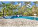 Backyard pool area surrounded by lush landscaping with in-pool loungers, a hot tub and a basketball hoop at 8418 Cape Dutch Loop, Myrtle Beach, SC 29572