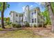 Exterior view of the rear of the home, showcasing a deck, landscaping and mature trees at 157 Egret Run Ln. # 514, Pawleys Island, SC 29585