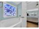 Relaxing bathroom featuring a soaking tub and a decorative window leading into the main bedroom at 174 Seville Dr., Murrells Inlet, SC 29576