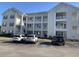 Condo building's exterior shows white siding, multiple balconies, and parking for residents at 901-9 West Port Dr. # 907, North Myrtle Beach, SC 29582