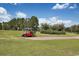 Vibrant red golf cart parked on a lush green course, with trees and blue skies in the background at 1106 Cherrystone Loop, Conway, SC 29526