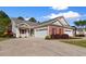 Charming home featuring a well-manicured lawn, brick accents, and a spacious driveway leading to an attached two-car garage at 120 Carolina Crossing Blvd., Little River, SC 29566
