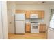 Bright kitchen featuring wood cabinets, white appliances, and laminate flooring at 1512 Hallborough Dr., Surfside Beach, SC 29575
