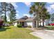 Single-story home with a well-manicured lawn and driveway, enhanced by mature trees on a partially clouded day at 174 Sussex Ct., Longs, SC 29568