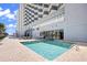 Exterior pool area featuring blue water, surrounding brickwork, hotel exterior, lounge chairs, and an ocean view at 2001 S Ocean Blvd. # 1303, Myrtle Beach, SC 29577