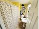 A compact bathroom with yellow walls, floral shower curtain, and pedestal sink at 202 28Th Ave. N # 5, North Myrtle Beach, SC 29582