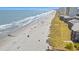 Wide, sandy beach with beautiful ocean and vacationers, featuring adjacent beachfront condo buildings at 208 Ocean Blvd. N # 228, North Myrtle Beach, SC 29582