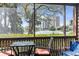 Relaxing screened porch with a table and chairs, offering serene waterfront views and a glimpse of distant buildings at 410 Melrose Pl. # 110, Myrtle Beach, SC 29572