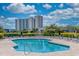 Inviting community pool surrounded by lounge chairs, green hedges, and luxurious high-rise condos at 410 Melrose Pl. # 110, Myrtle Beach, SC 29572
