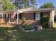 Charming brick home with covered front porch, a garden with a rock water feature, and an American flag at 4204 Peachtree Ln., Myrtle Beach, SC 29588