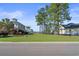 A street view of a grassy, vacant lot with tall trees in a desirable waterfront community at 573 Starlit Way, Myrtle Beach, SC 29579
