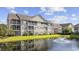 Condominium exterior featuring screened porches, well-maintained landscaping, and a serene lake with fountain at 5882 Longwood Dr. # 201, Murrells Inlet, SC 29576