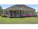 A serene backyard with a screened porch and vibrant pink azaleas lining the well-maintained lawn at 610 Cocas Dr., Myrtle Beach, SC 29579